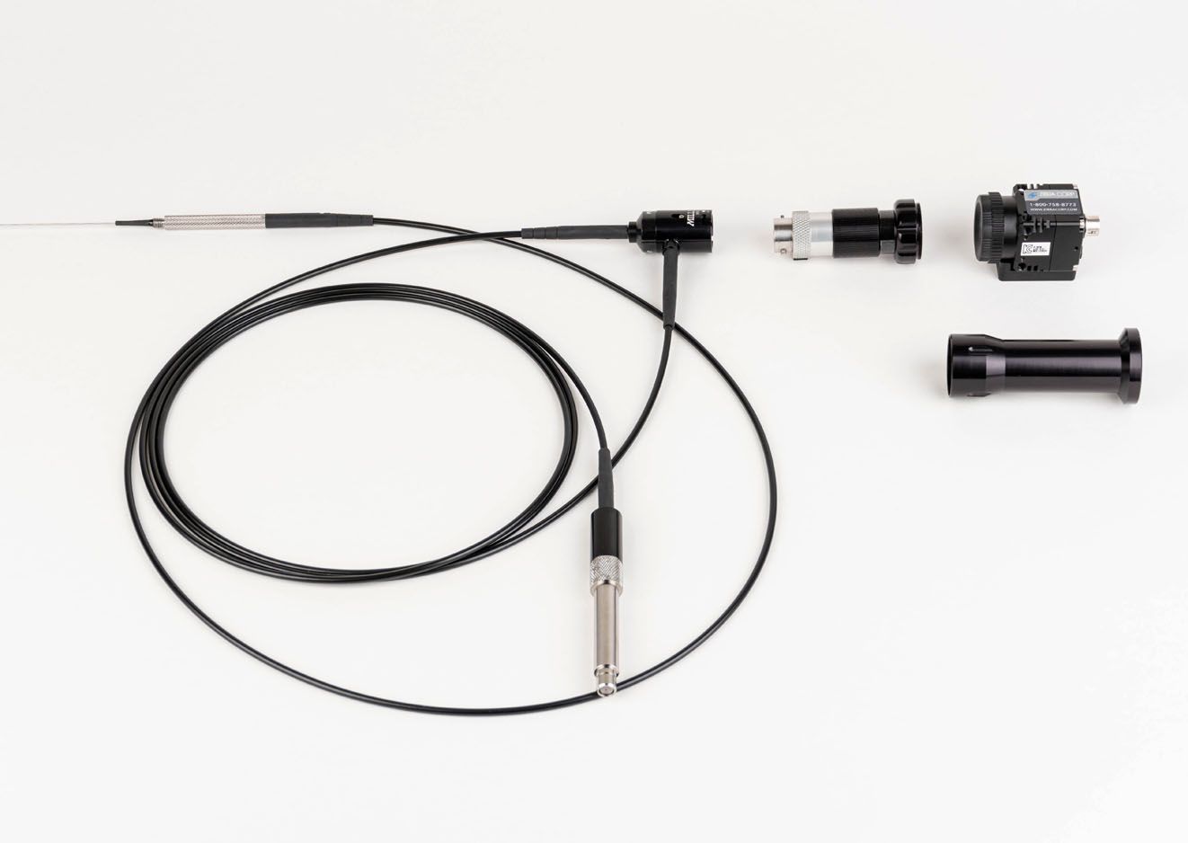 A black cable with a metal tip is laying on a white surface