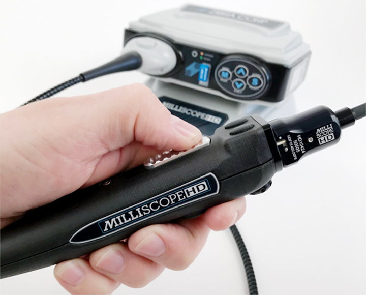 hand holding a black object with 'MilliscopeHD' on it