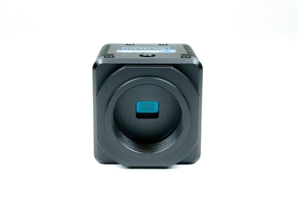 A small black camera with a blue lens on a white background