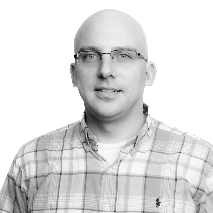 headshot of man wearing plaid shirt in black and white